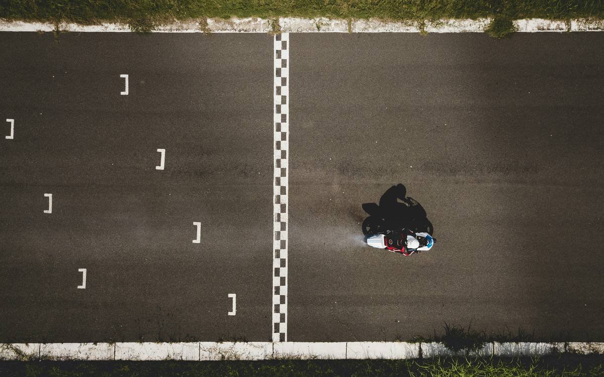 A MotoGP rider training on a simulator with detailed telemetry data visible on nearby screens.