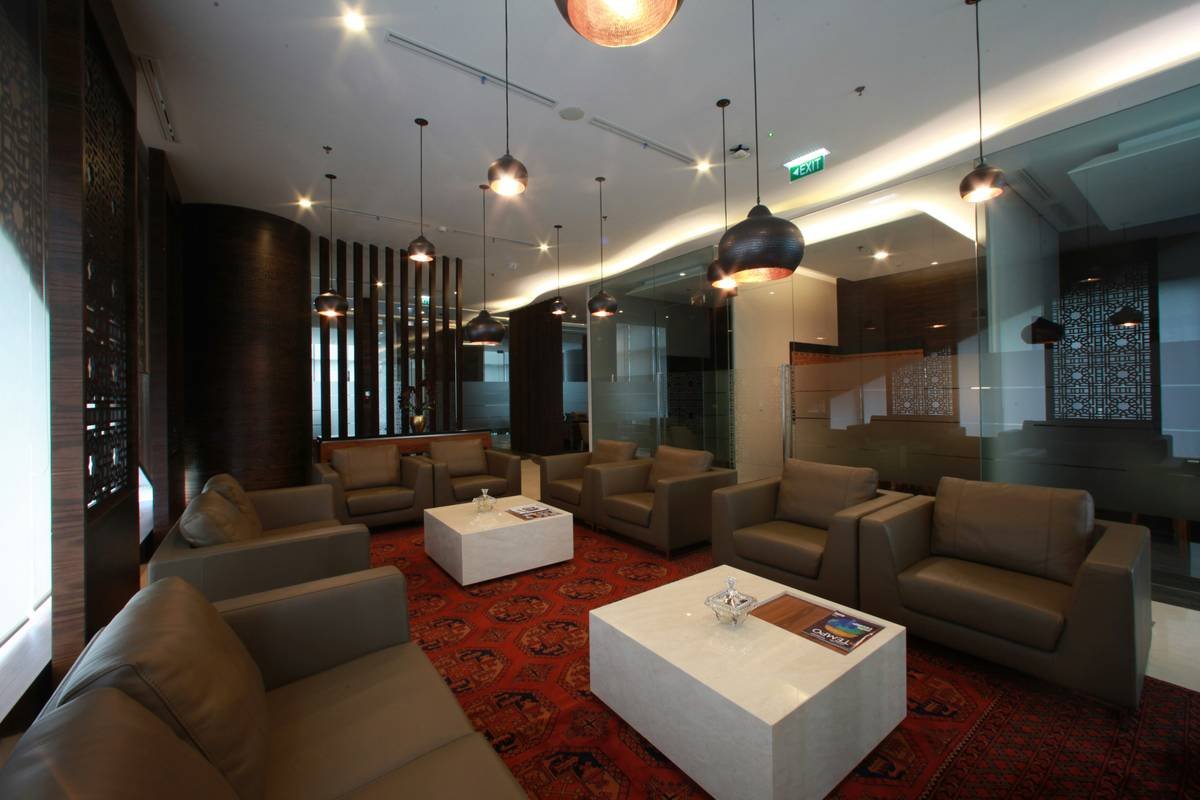 Luxury lounge area with comfortable seating and large TVs showing live MotoGP action.